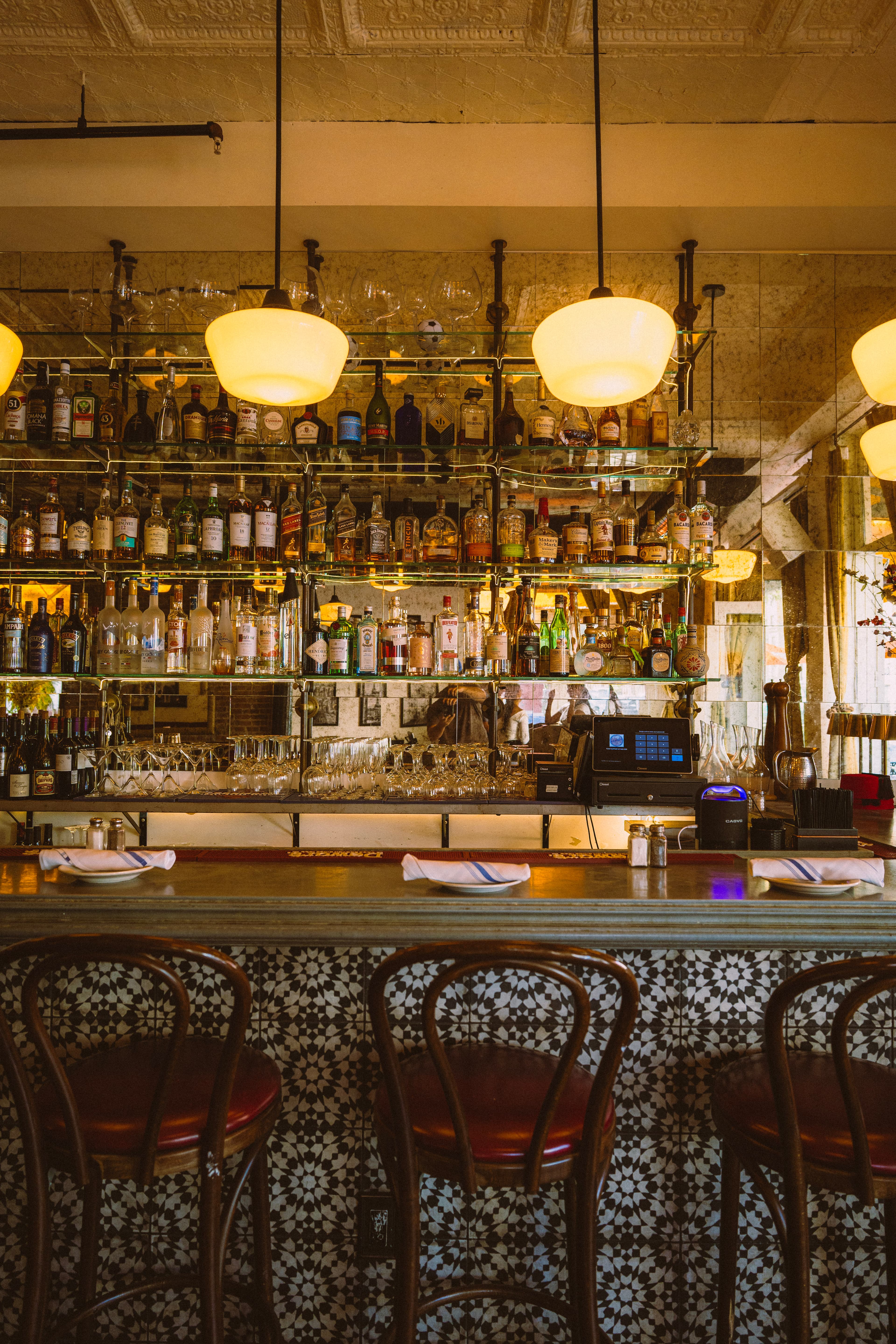 Red-seated bar stools in front of the tiled Barbès bar
