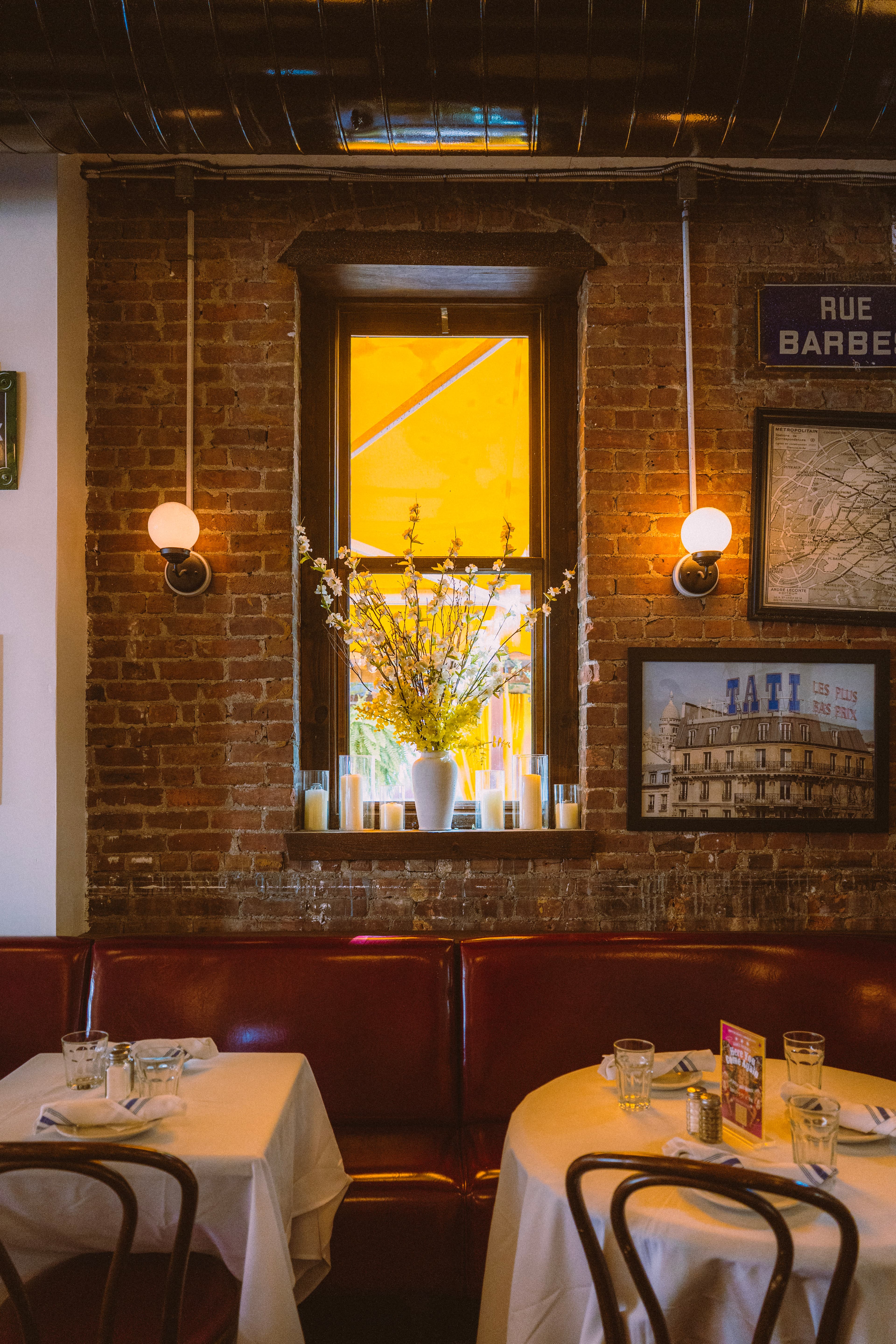 Brick wall, sunlit window and framed prints above the booths