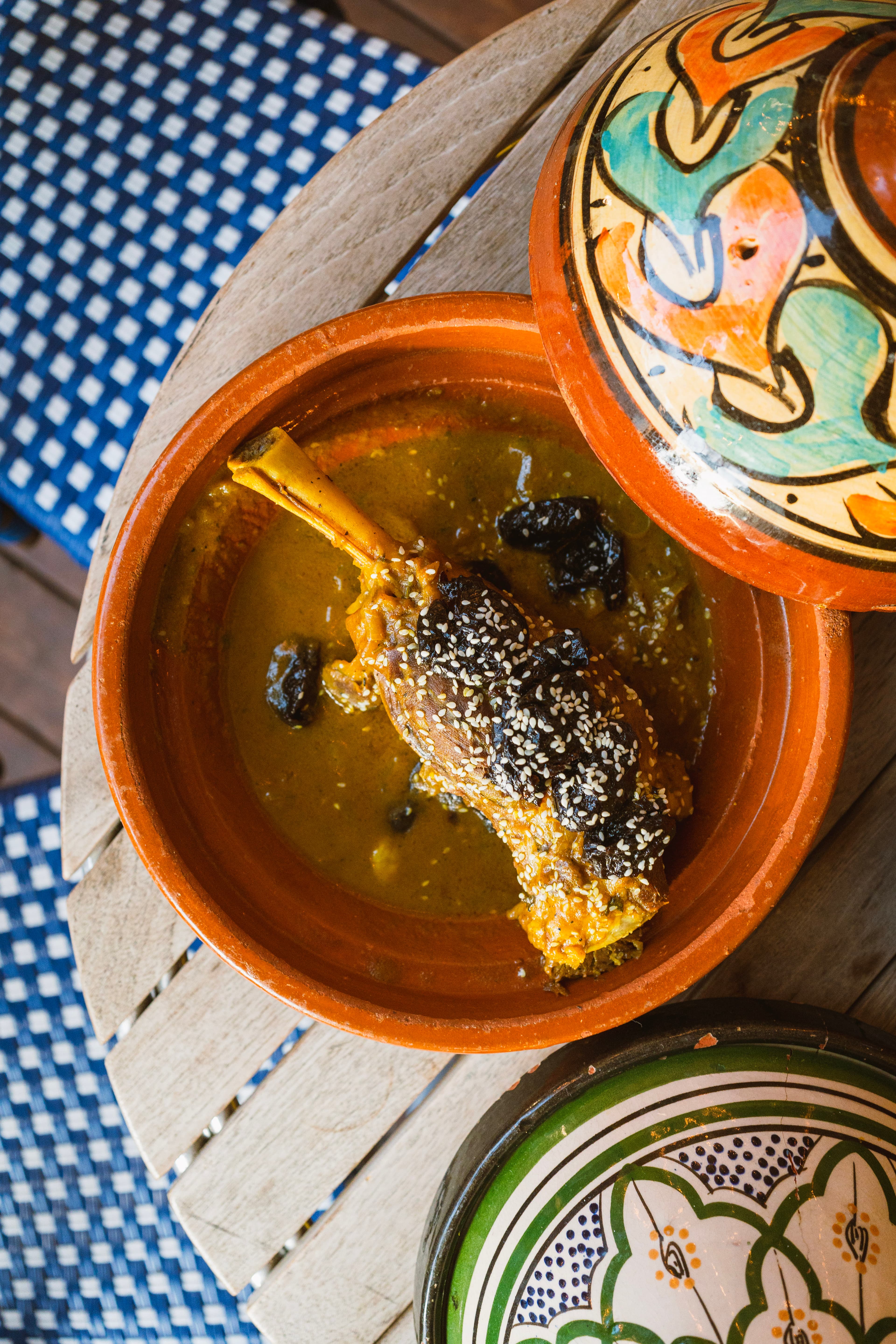 Lamb shank tagine with prunes and sesame seeds in a clay dish