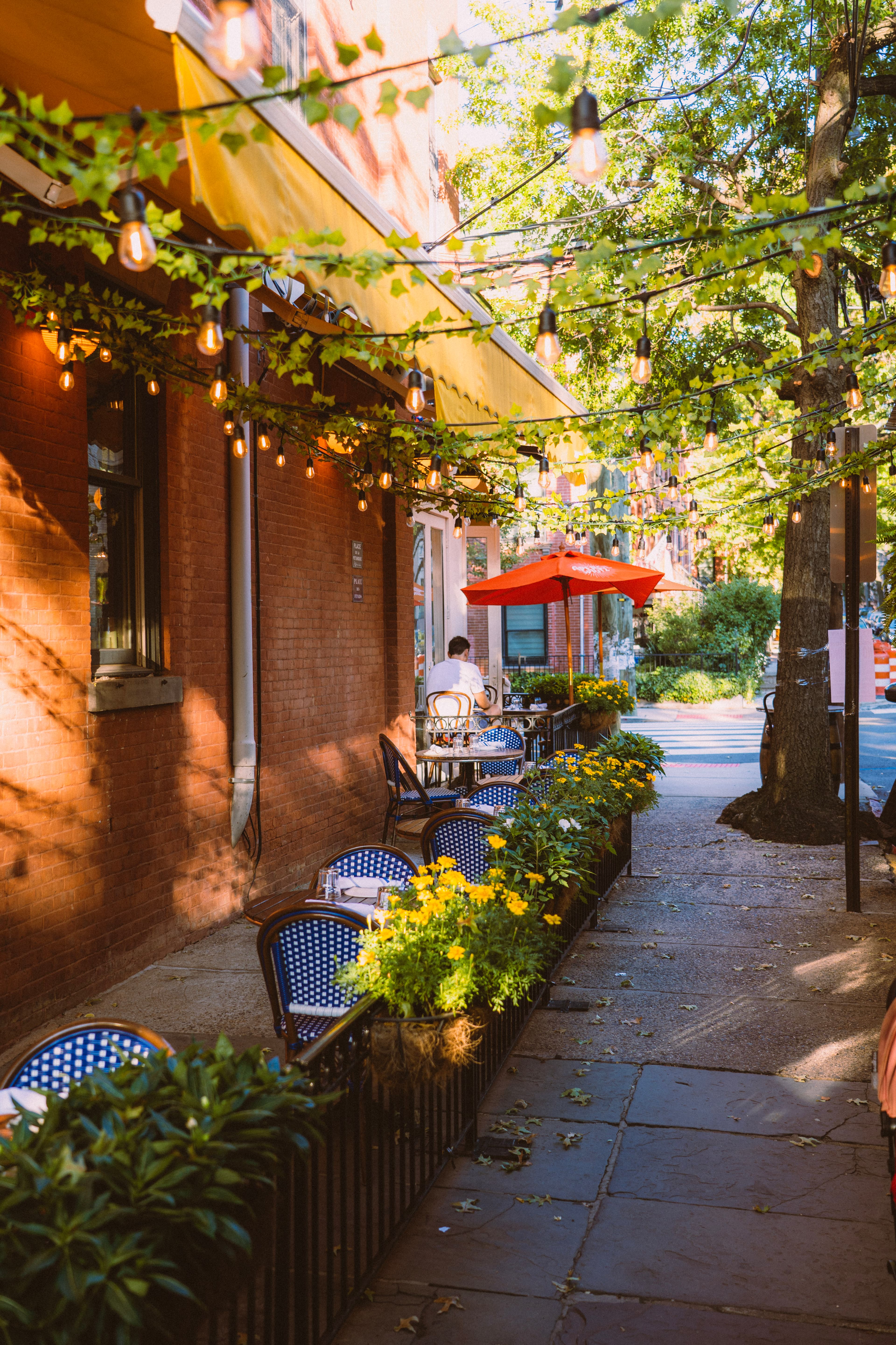 Barbès sidewalk patio in golden-hour light under string lights